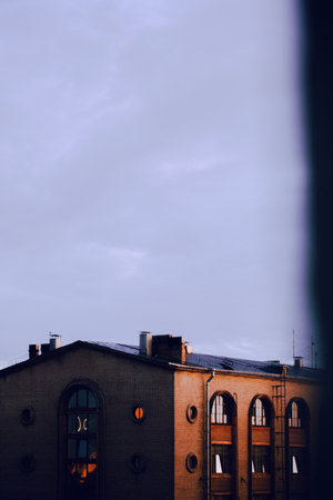The old factory building stands against a bluish, cloudy sky on a summer evening, creating a stunning urban landscape.の写真素材