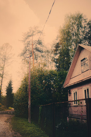 A beautiful pink wooden house stands near the edge of the forest, illuminated by the light of the rising sun. The warm and cozy atmosphere of this native home is inviting.の写真素材