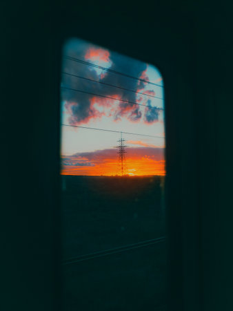 From the window of the moving train, a beautiful landscape unfolds. A bright orange sunset...