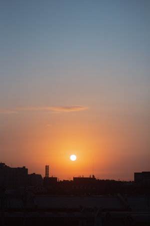 A beautiful gentle dawn. The sun is rising over the dark rooftops of a big city, creating a...