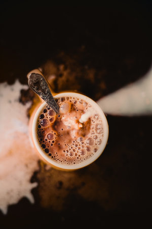 Top view of a cup of hot, fragrant coffee with cold milk poured into it. The process of creating a delicious drink for the morning. Messy.の写真素材