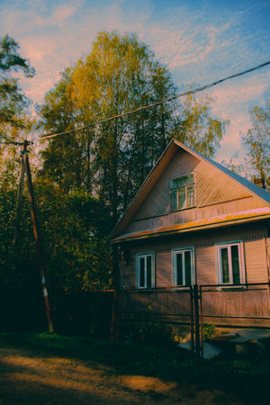 A charming old wooden house sits near the edge of the forest, bathed in the light of the sun. The warm and inviting atmosphere of this cozy home.の写真素材