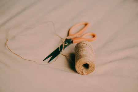On the beige fabric, there is a coil of hemp rope and a pair of modern scissors. This is a process...