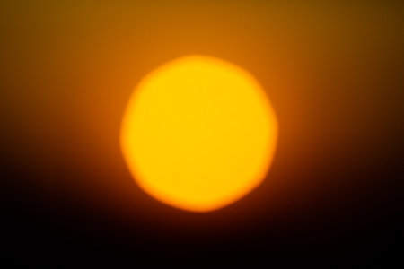 A blurred, bright solar disk against a dark orange sky at sunrise. The backdrop of the sky is breathtaking.の写真素材