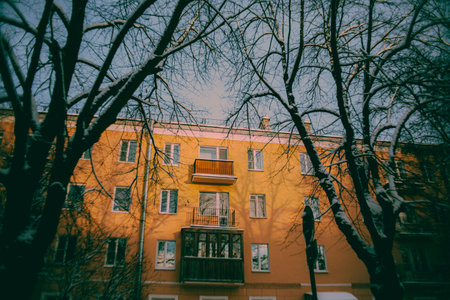 On a sunny winter's day, the yellow residential building was illuminated by the rays of the sun. It was a typical winter day in the city, with the comfort of the city's courtyards.の写真素材