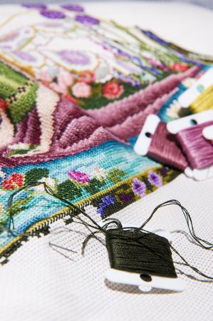 Colorful cross stitch art in the making, showing various color threads.