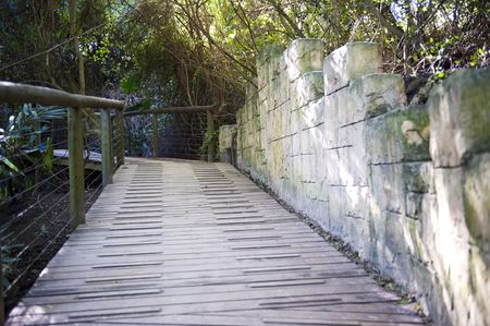 Wooden bridge with an old rock wall on the right.