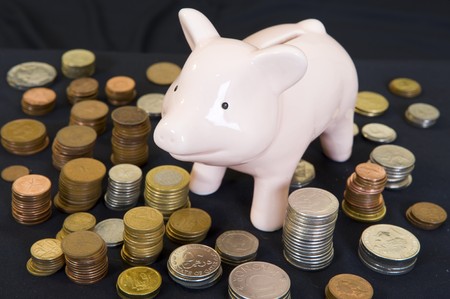 Piggybank with various international currencies on a black background.の写真素材