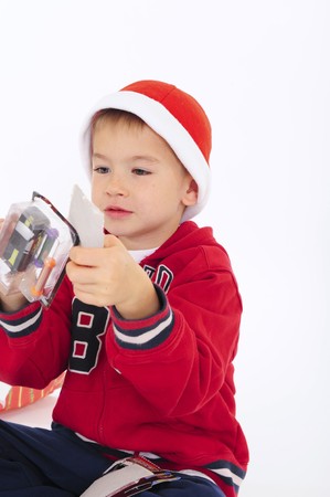 Young boy opening small Christmas present in Santa Hat. White Background.の写真素材