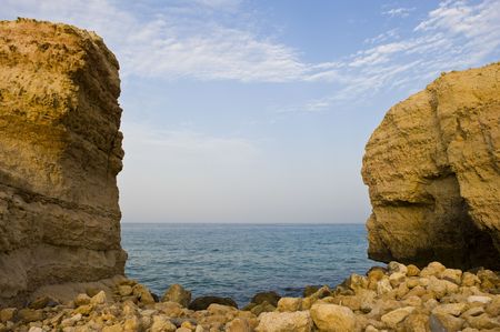 A gap in the mountain forming a small rocky beach with the sea visible in the background.の写真素材