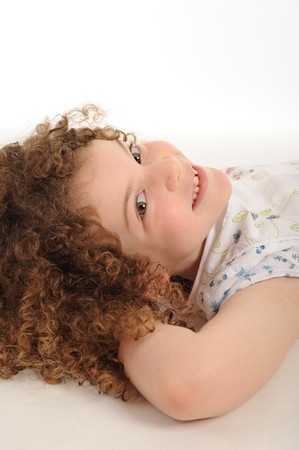A gorgeous little girl with curly hair in the studio, white background.の写真素材