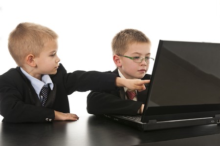 Two little boys dressed up in suits pretending to be businessmen. Isolated on white.の写真素材