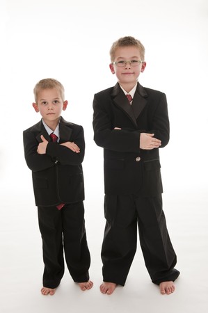 Two little boys dressed up in suits pretending to be businessmen. Isolated on white.の写真素材