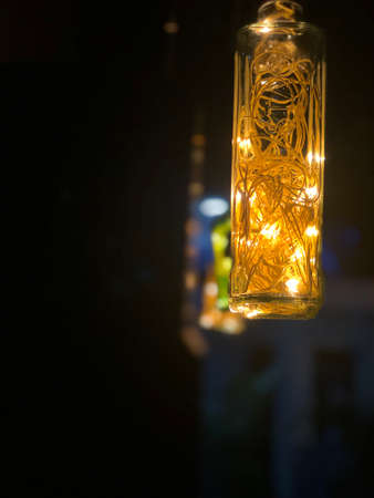 Glass bottles hanging with fairy lights insideの写真素材