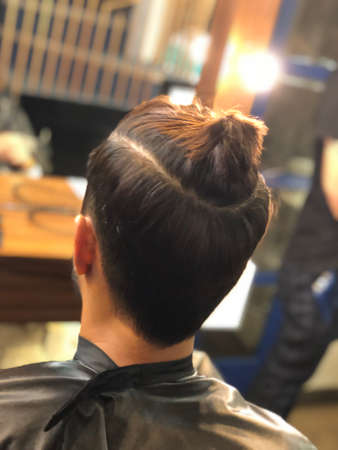 Man with ponytail at a salon getting ready for his new haircutのeditorial素材