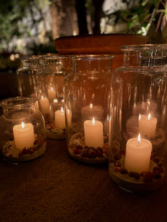 Candles burning in beautifully glass jars with sand and pebblesの写真素材