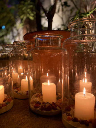 Candles burning in beautifully glass jars with sand and pebblesの写真素材