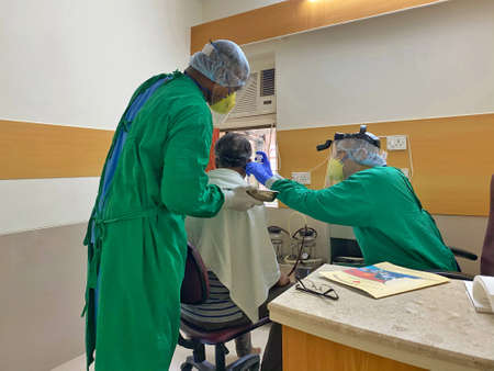 ENT Doctors in PPE examining a patient in COVID timesのeditorial素材