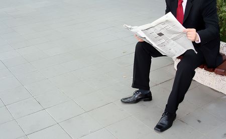 Businessman reading newspaper on the benchの写真素材