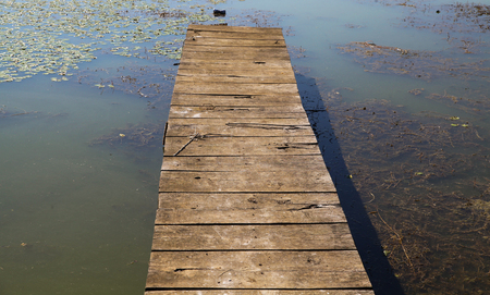 Small old lake pier made from wood on surface of water on early morningの写真素材