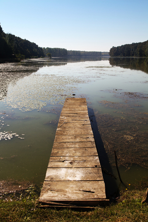 Small old lake pier made from wood on surface of water on early morningの写真素材