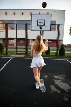 Beautiful young athletic girl, playing with the ball on the basketball court outdoors.の写真素材
