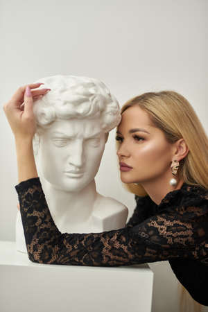 girl hugs a bust of david on a white backgroundの写真素材