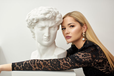 girl hugs a bust of david on a white backgroundの写真素材