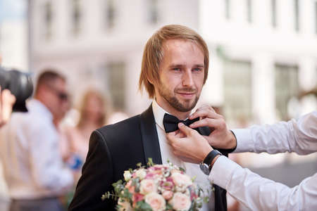 The groom straightens the bow tie. Man straightening his black bow-tie. Getting Ready. wedding. blurred imageの写真素材