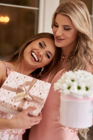 Two happy friends open a gift box, in a restaurant on a summer dayの写真素材