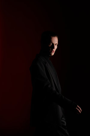 Portrait of a young man in a black coat. Studio shot.