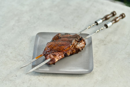 Grilled pork ribs on a gray plate with a metal skewerの写真素材