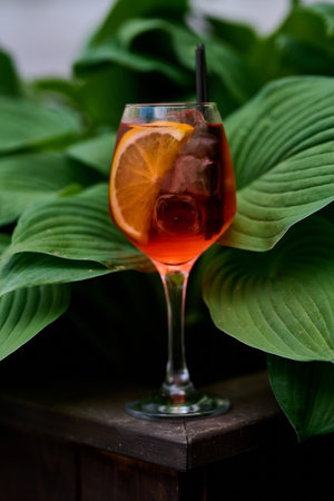 Cocktail in a glass on a wooden table with green leavesの写真素材