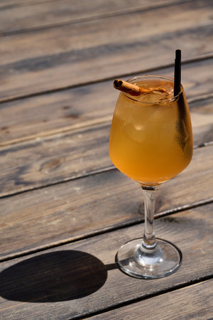 Cocktail with orange juice and cinnamon stick on a wooden tableの写真素材