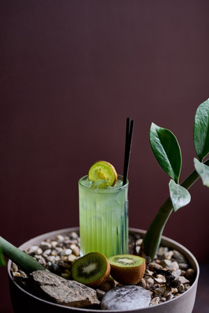 Kiwi juice in a glass with a straw and a kiwi on a wooden backgroundの写真素材