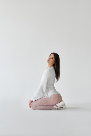 Young beautiful ballerina sitting on the floor over white background.の写真素材