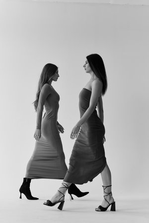 Two beautiful young women in evening dresses on white background. Studio shot.の写真素材