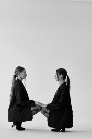Two young women in black on white background. Studio shot.の写真素材