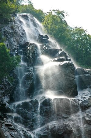 Beautiful rocky waterfall surrounded by green mountain forest.の写真素材
