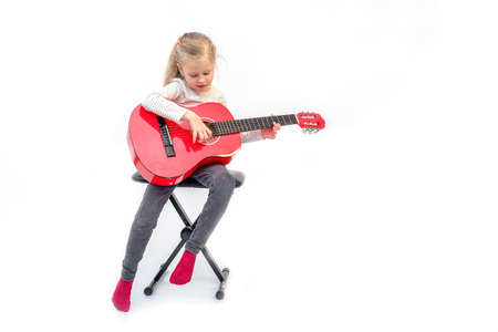 blond litle girl sits and plays the red guitarの写真素材