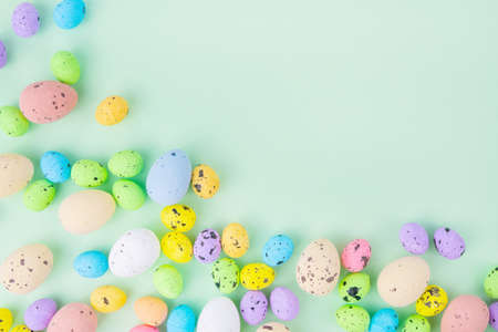 Top view of set of multicolored quail eggs placed on blue background on Easter Day