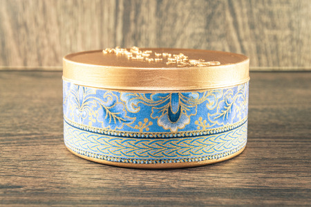 Handmade candle made in the golden rounded box decorated with textured fabric. Scenery and wooden background.の写真素材