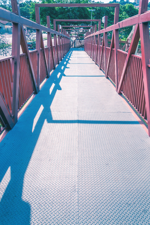 Red bridge with metal structure. Lines in perspective, long pedestrian crossing.の写真素材