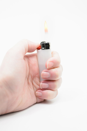 Hand lighting a lighter, fire coming out of the lighter.の写真素材