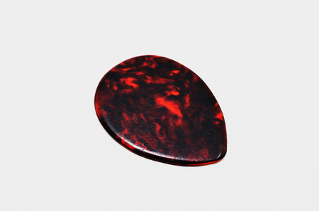 Used dark brown guitar pick isolated on white background.の写真素材
