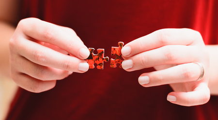 Jigsaw Puzzle Game: Hands of a woman holding and matching two pieces of a puzzle.
