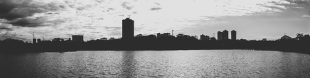 Silhouette of the lake and the city on the background on a cloudy day. Panoramic, black and white photo.の写真素材