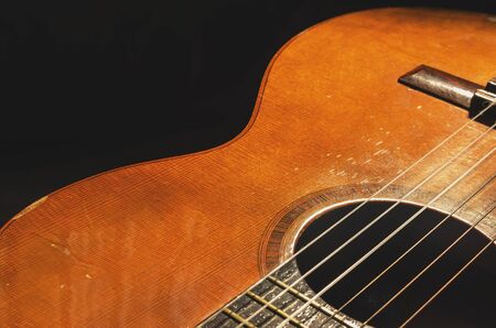 Shapes and lines of an old acoustic guitar, the body curves, sound hole, frets and old rusty nylon...