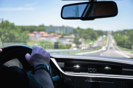 Driving a car on a long highway. View through the inside of a car during a car trip on a Brazilian road.の写真素材