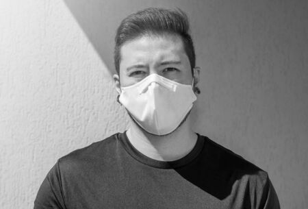 Portrait of an adult man wearing a white face mask. Black and white photo.の写真素材